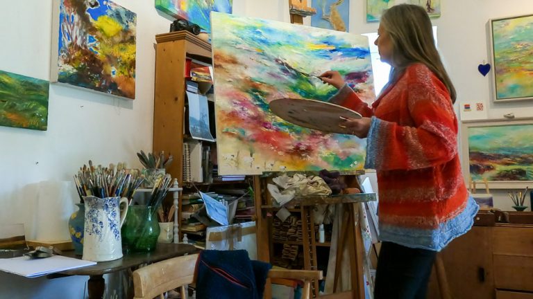 Artist Melody Hawtin in her studio painting a new landscape painting of Exmoor National Park